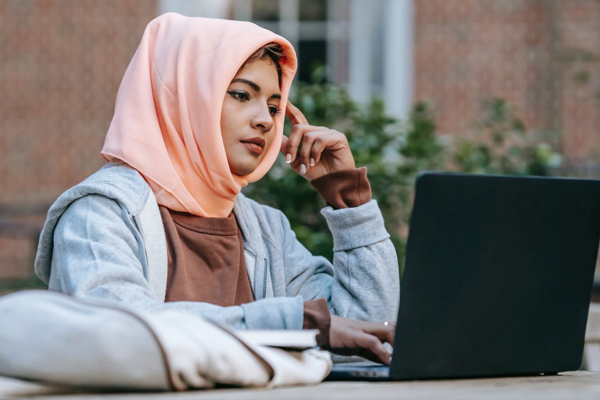 thoughtful young arab woman studying online on netbook in courtyard